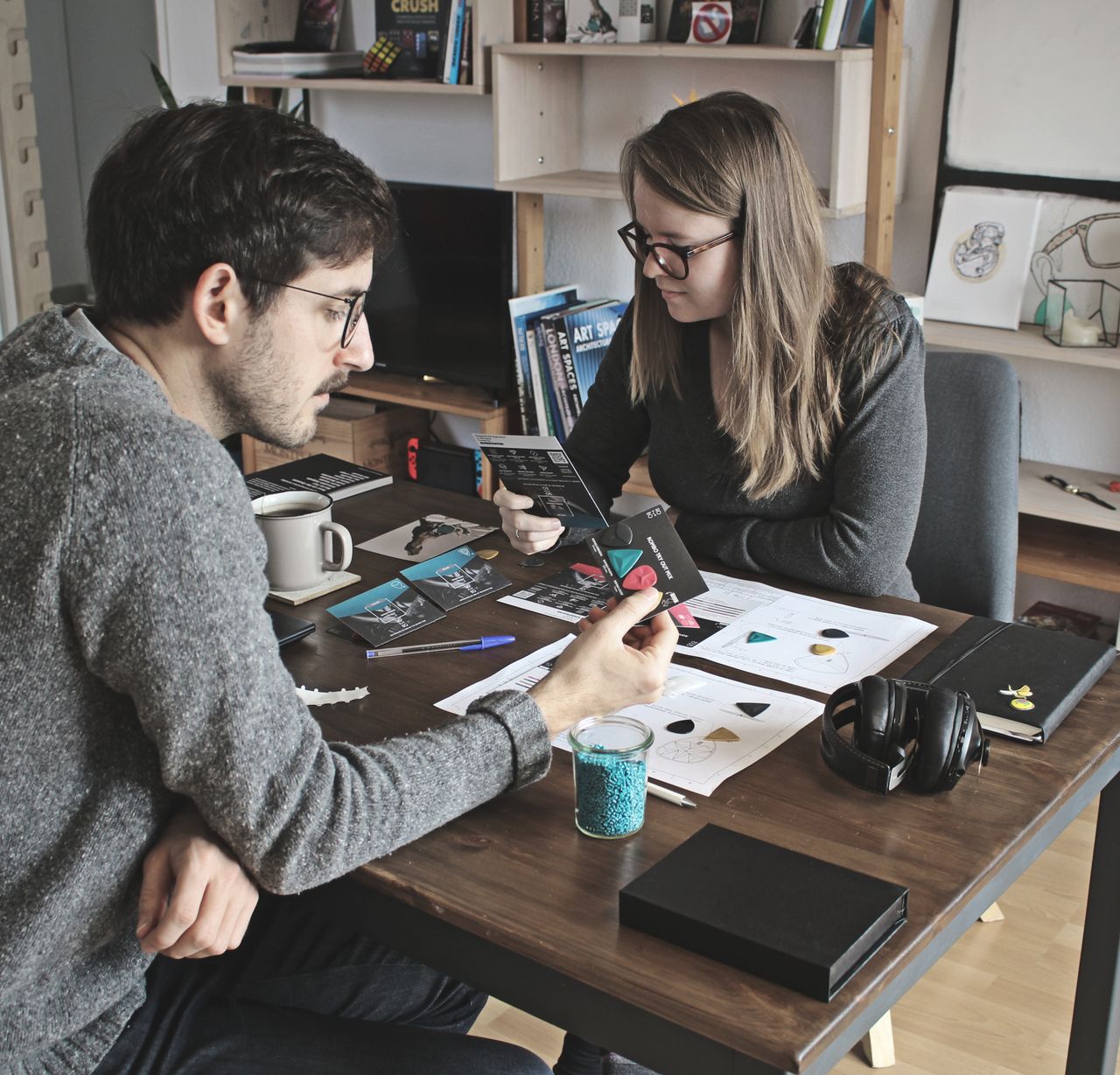 Two adults collaborating on a design project at a table in a modern living room setting.
